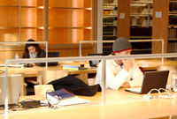 Two students study in the law library at tables with laptop computers